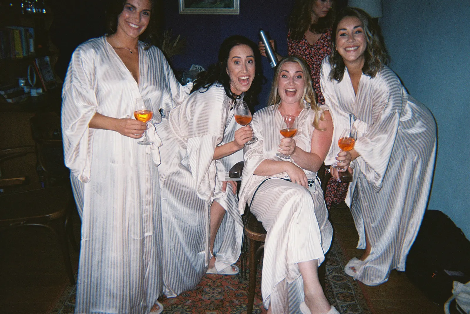 The bride and her bridesmaids in matching robes, spritz in hand