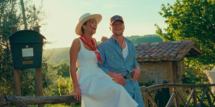 Nina and Kelvin laughing on a wooden fence in the Italian sun