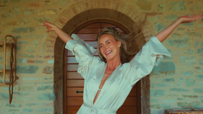 Kim throwing her arms in the air in front of an old wooden door in Italy